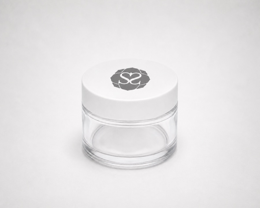 Empty glass jar with a white lid printed with the salonsolids emblem