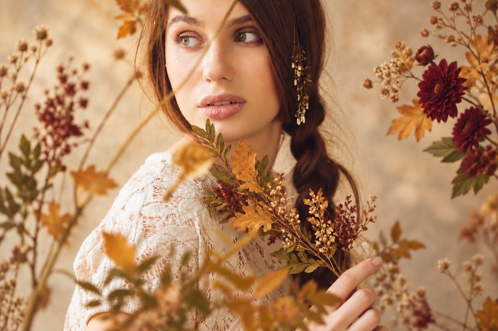 A woman with a braid among dried autumn flowers and dahlias